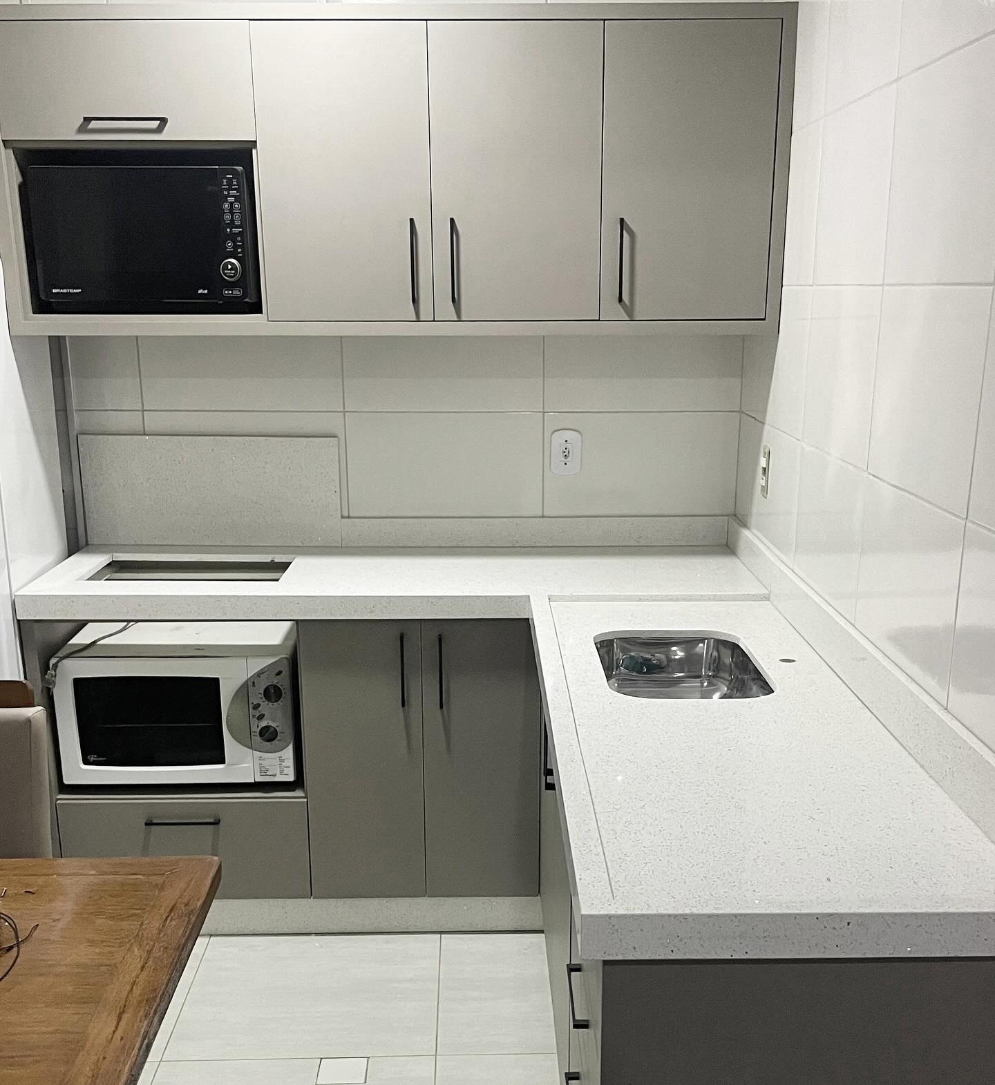 Cozinha com bancada em superfície clara, recorte para cooktop e cuba embutida