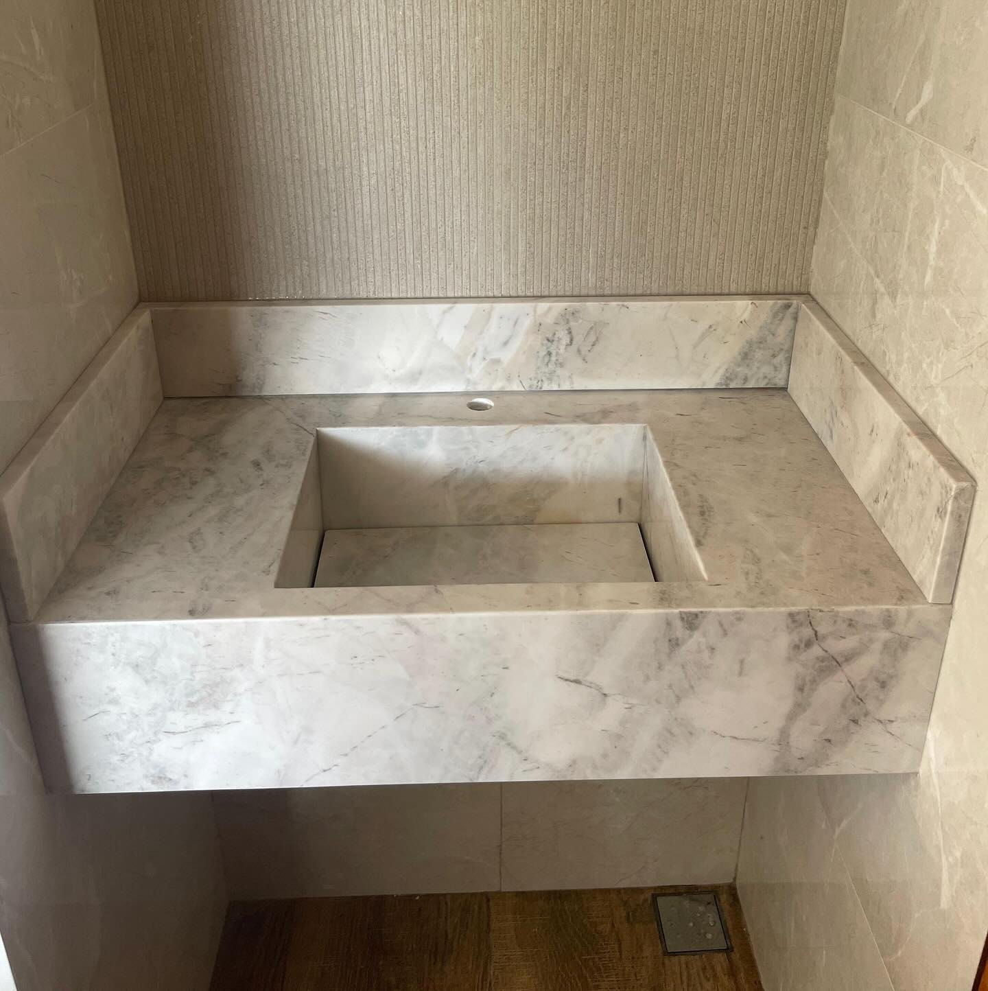 Lavabo em rocha natural clara com cuba esculpida e frontão em peça única